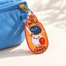 The Battle Is The Lord's embroidered Christian keychain hanging from a blue bag