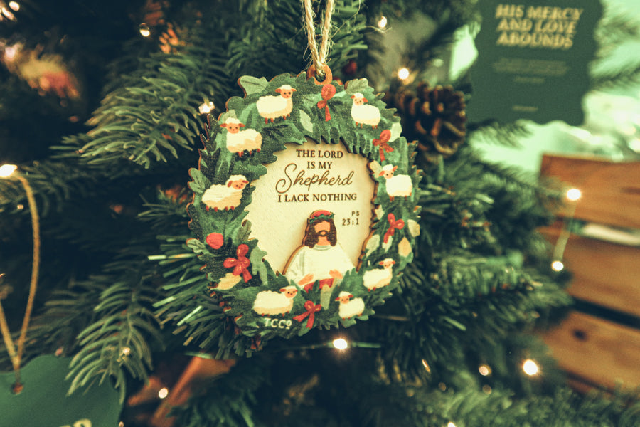 'The Lord is My Shepherd' Psalm 23:1 Christmas wreath ornament decorated with sheep and holly, hanging on a festive Christmas tree.