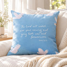 The Lord Watches Over You Psalm 121:8 blue cushion cover with white doves on a cream sofa beside a knitted throw.