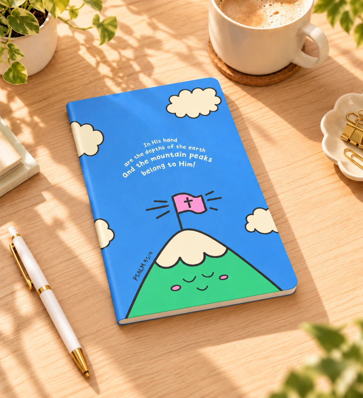 The Mountain Peaks Belong to Him A5 Christian notebook styled on a warm sunlit desk