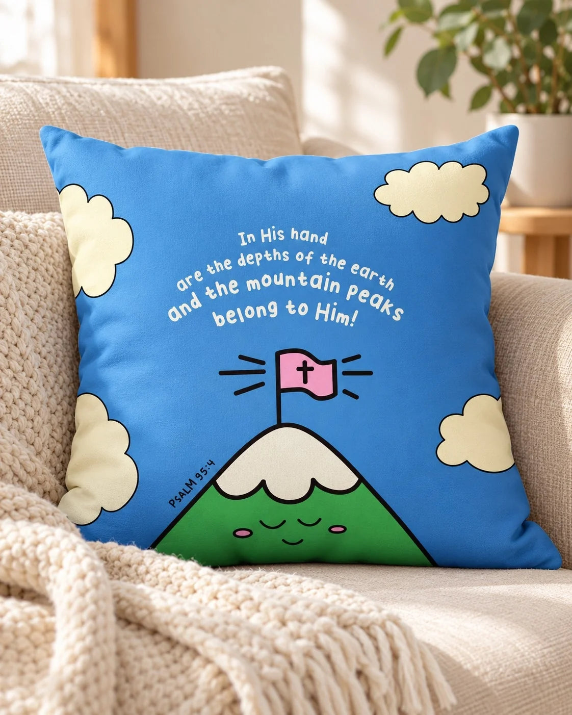 The Mountain Peaks Belong to Him Psalm 95:4 blue cushion cover on a cream sofa.