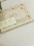 Close-up of This Little Light prayer journal spine with floral embroidery and ribbon bookmarks