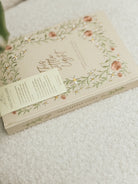 Close-up of This Little Light prayer journal spine with floral embroidery and ribbon bookmarks