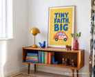 Tiny Faith Big God poster displayed above a wooden console in a bright playful living space