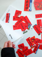 Hand holding mini Chinese New Year couplet sticker pack with festive red blessing designs