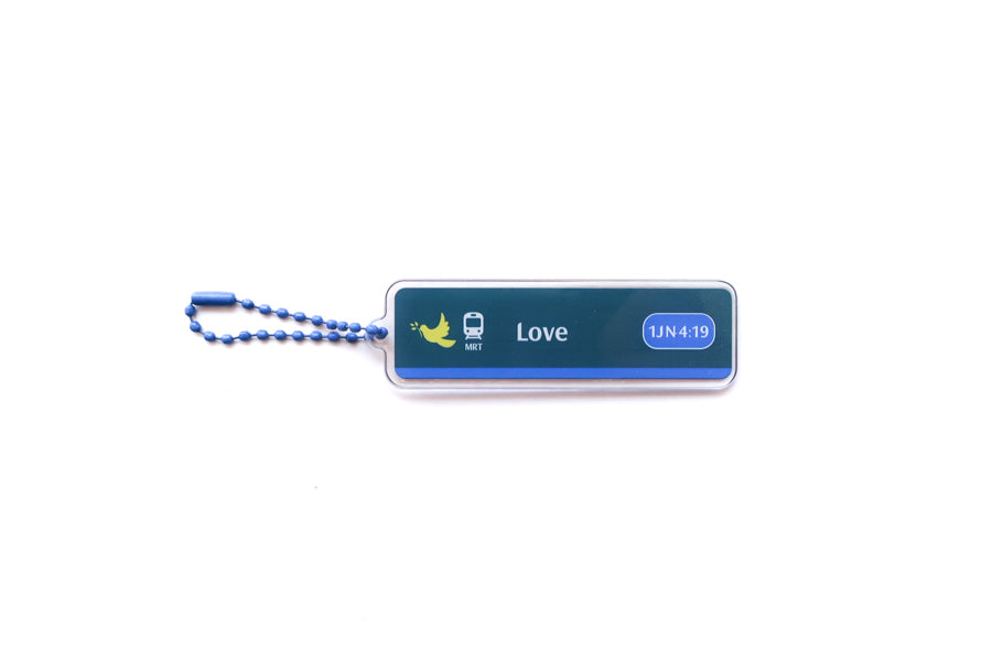 Front view of Train Station Love Christian acrylic keychain featuring 1 John 4:19 with blue ball chain