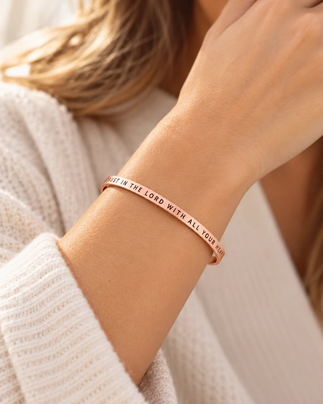 Rose gold Trust in the Lord with All Your Heart verse band worn on a wrist in natural sunlight