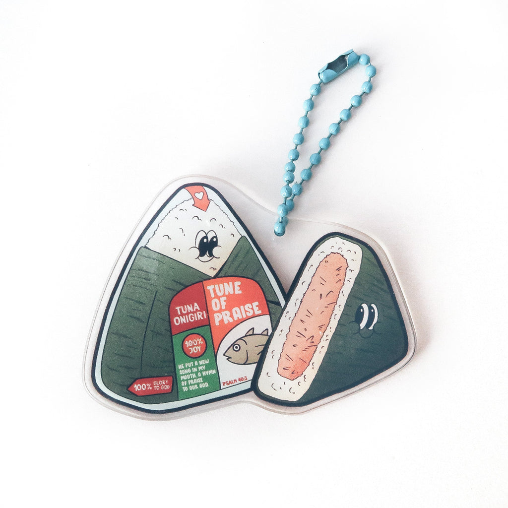 Faith-inspired tuna onigiri keychain featuring 'Tune of Praise' text from Psalm 96:1, blending food imagery with Christian encouragement.