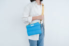 Cyan pong pong bag worn with a yellow-accented strap, designed for everyday use and style.