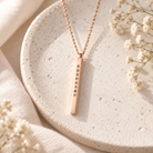 Rose gold personalised vertical bar necklace displayed on a neutral ceramic tray