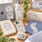 Everyday Believer Vibe Check Christian stickers placed on a laptop, bottle, notebook, phone case and accessories in a bright desk setting.