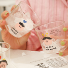 Two glass mini cups with designs and messages "We are loved" and "We are not alone," symbolizing love and connection.