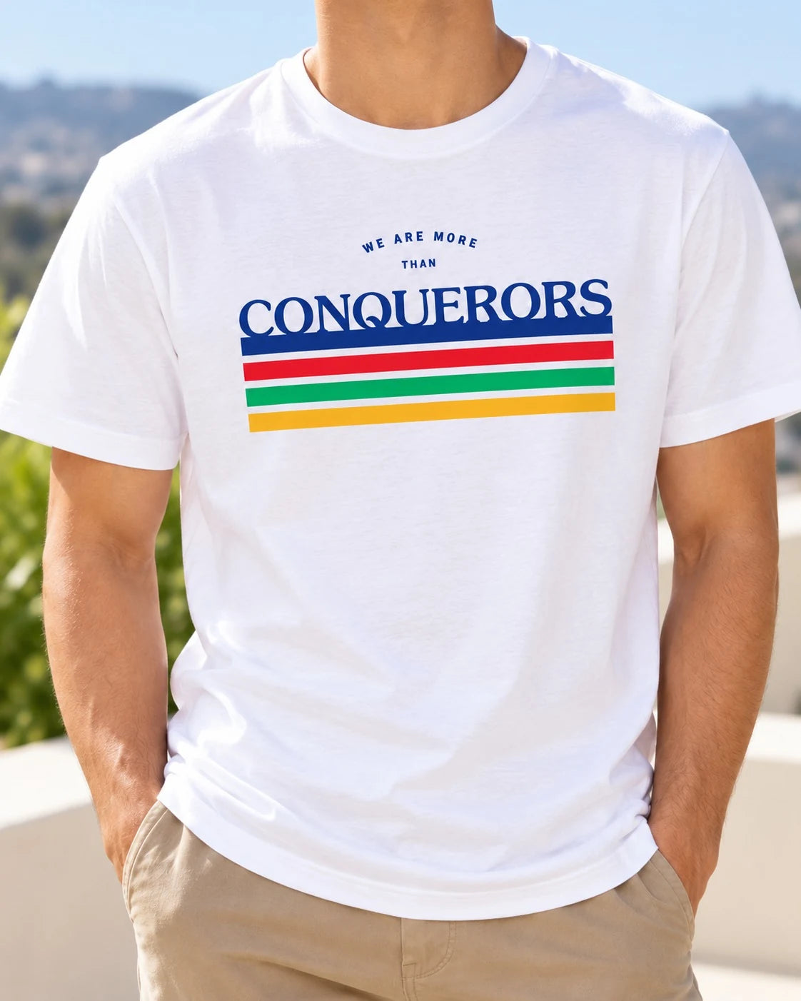 Lifestyle photograph of a man wearing the white We Are More Than Conquerors Christian T-shirt.