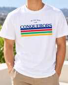 Lifestyle photograph of a man wearing the white We Are More Than Conquerors Christian T-shirt.