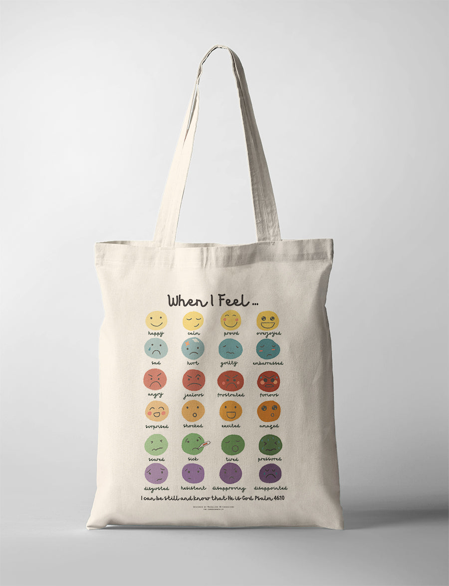Christian kids tote bag featuring a feelings chart with illustrated emotions and the verse “Be still and know that He is God” from Psalm 46:10.