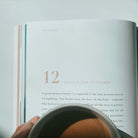 An open page from the Who Is Jesus book featuring an inspiring quote about grace, with dried lavender sprigs on a sunlit table, reflecting simple happiness and faith.