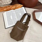 Brown canvas drink carrier bag with “Today is gonna be a wonderful day, for God has blessed me” text beside an open Bible