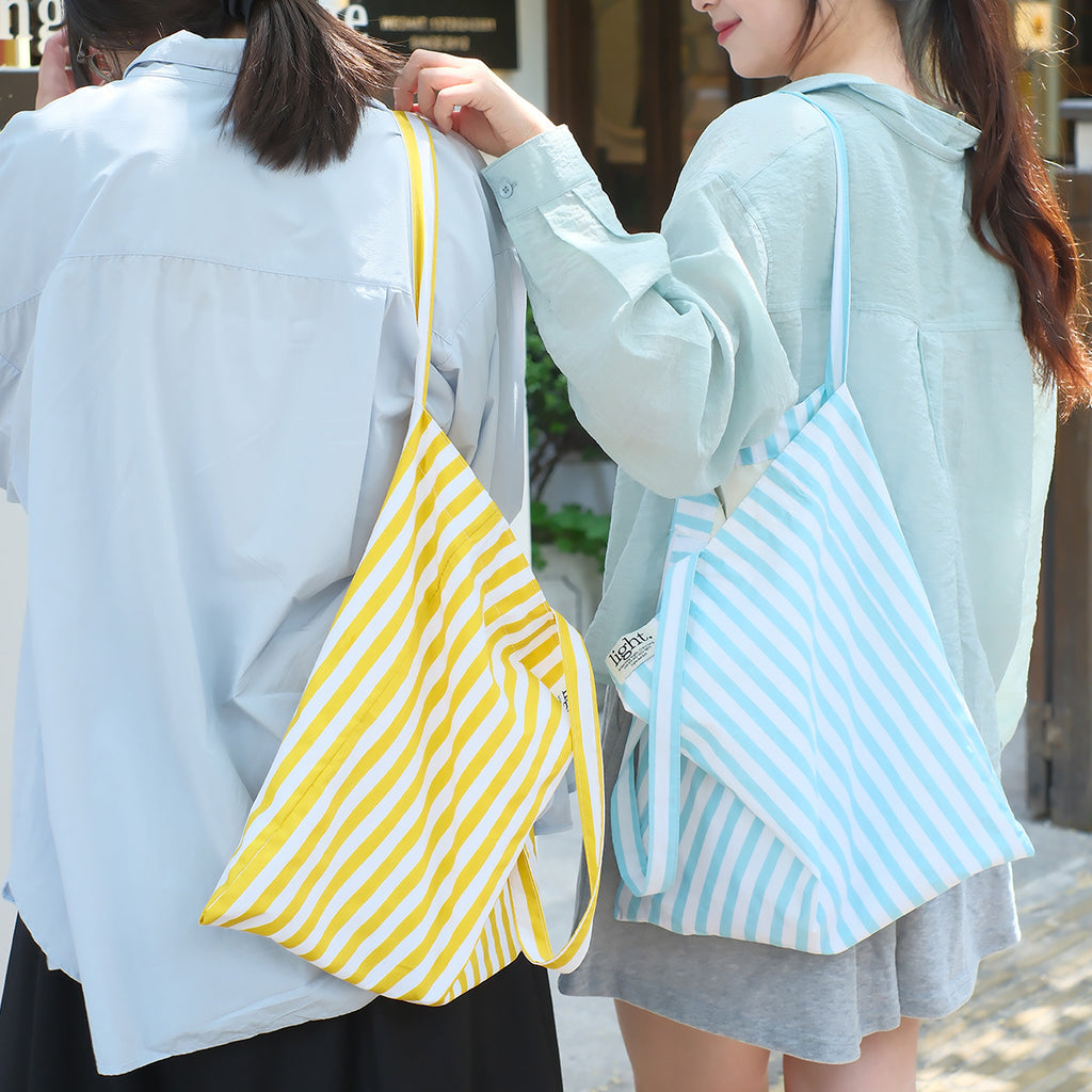 Two women wearing yellow and blue striped cotton tote bags by Light and Salt brand, eco-friendly reusable bags for shopping