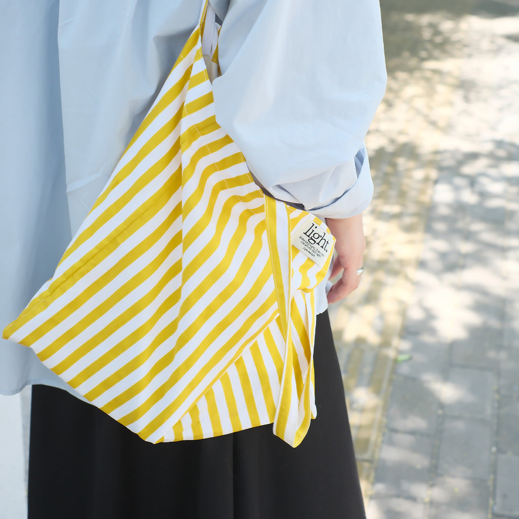 Close-up of a yellow striped cotton tote bag, an eco-friendly reusable bag ideal for shopping and casual outings.