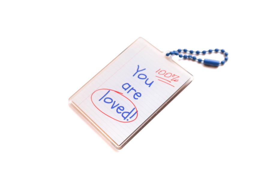 Angled back view of Christian acrylic keychain with “You are loved!” notebook paper design