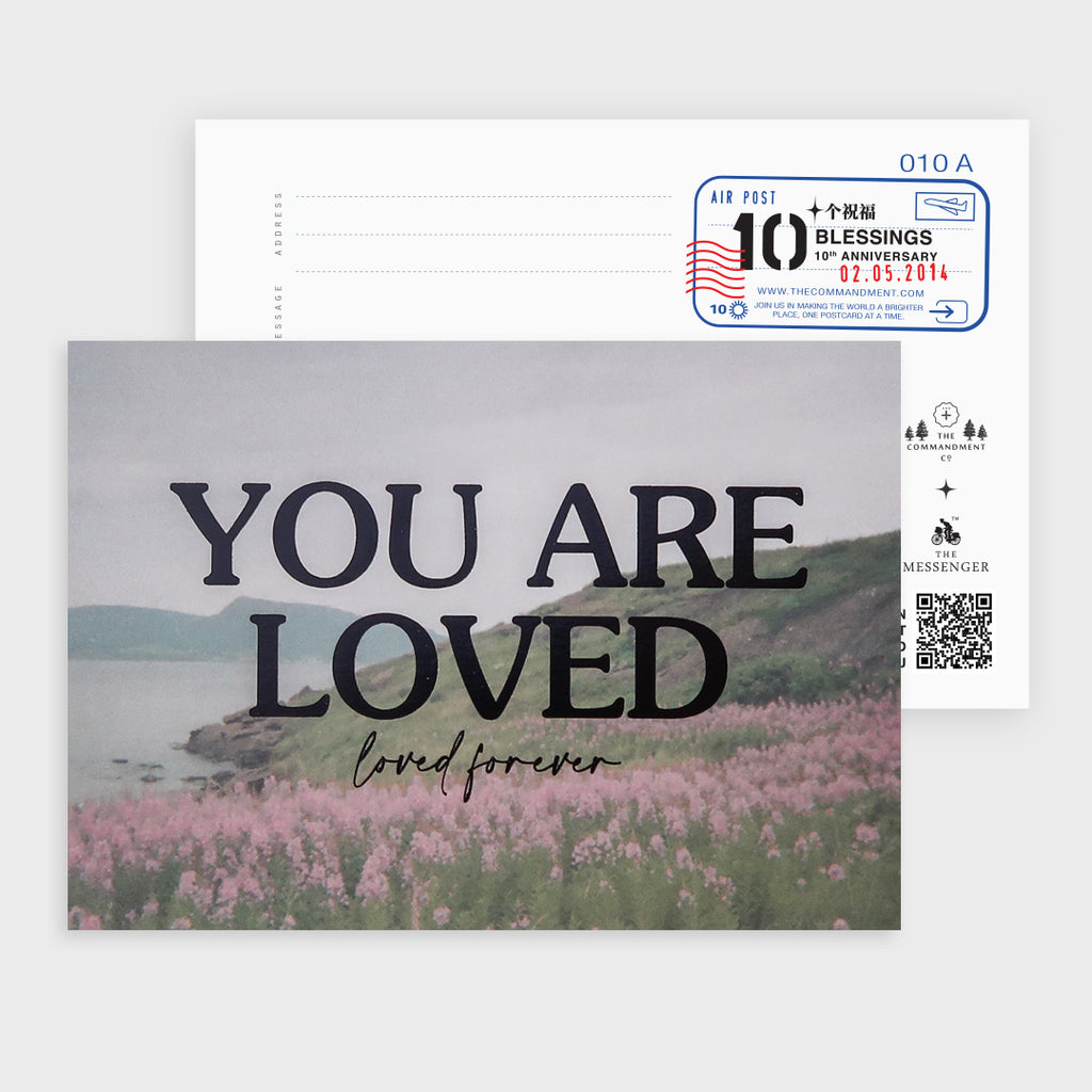 A postcard with a scenic background of a peaceful field of pink flowers and the comforting message "You Are Loved, loved forever," designed to inspire feelings of love and belonging.