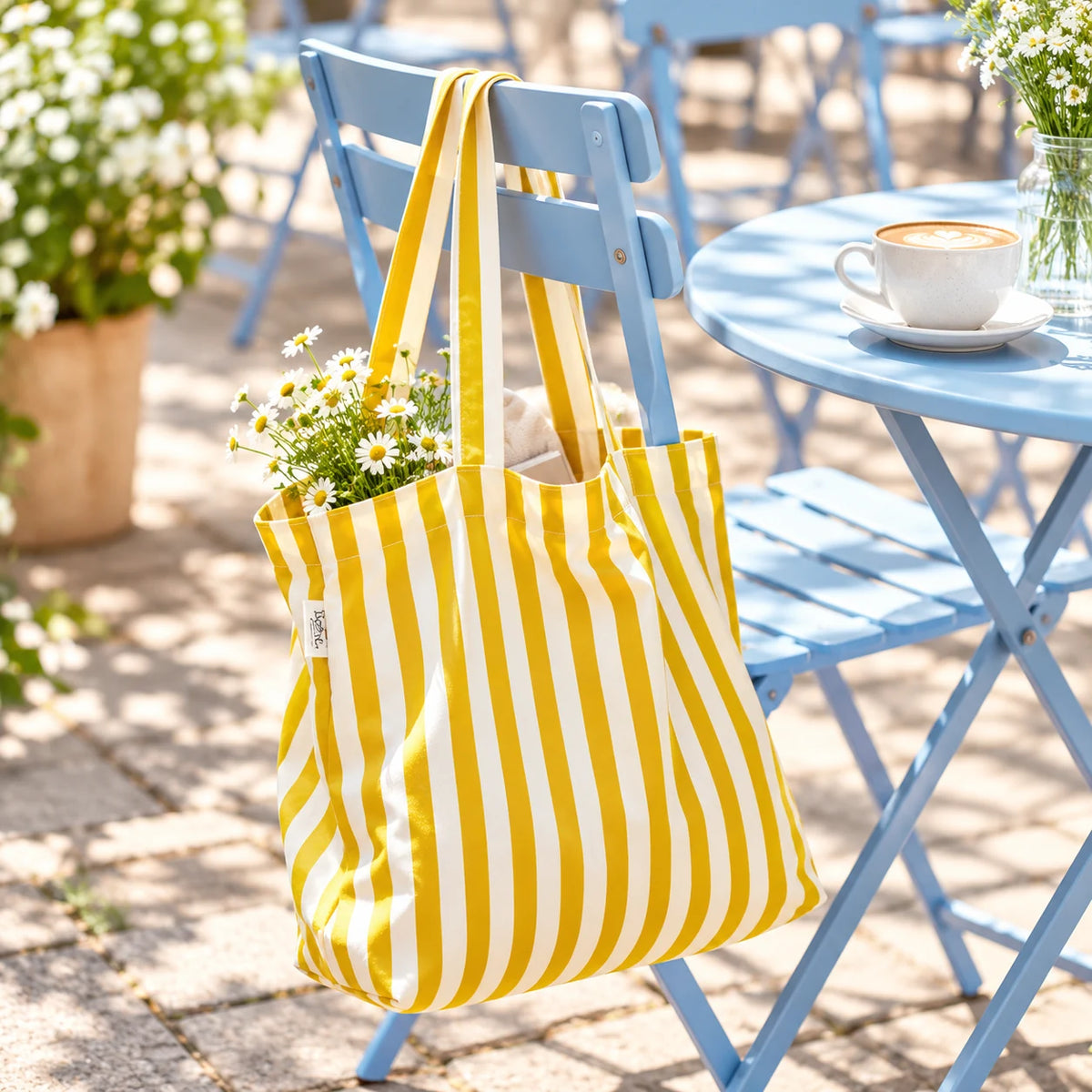 Yellow and white striped You Are My Light canvas tote bag hanging on a blue outdoor café chair