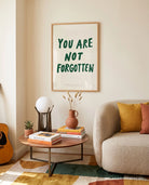 You Are Not Forgotten Christian poster displayed in a warm living room above a side table and sofa