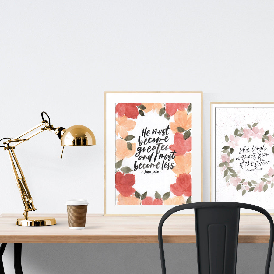 A3 beautiful calligraphy with flowers poster placed standing next to a smaller A4 sized floral calligraphy poster on a wooden table. Inspiring home decor ideas.