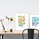 A3 beautiful calligraphy poster placed standing next to a smaller A4 sized calligraphy poster on a wooden table. Modern Christian home interior design ideas.