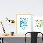 A3 beautiful calligraphy poster placed standing next to a smaller A4 sized calligraphy poster on a wooden table. Modern home interior design ideas.