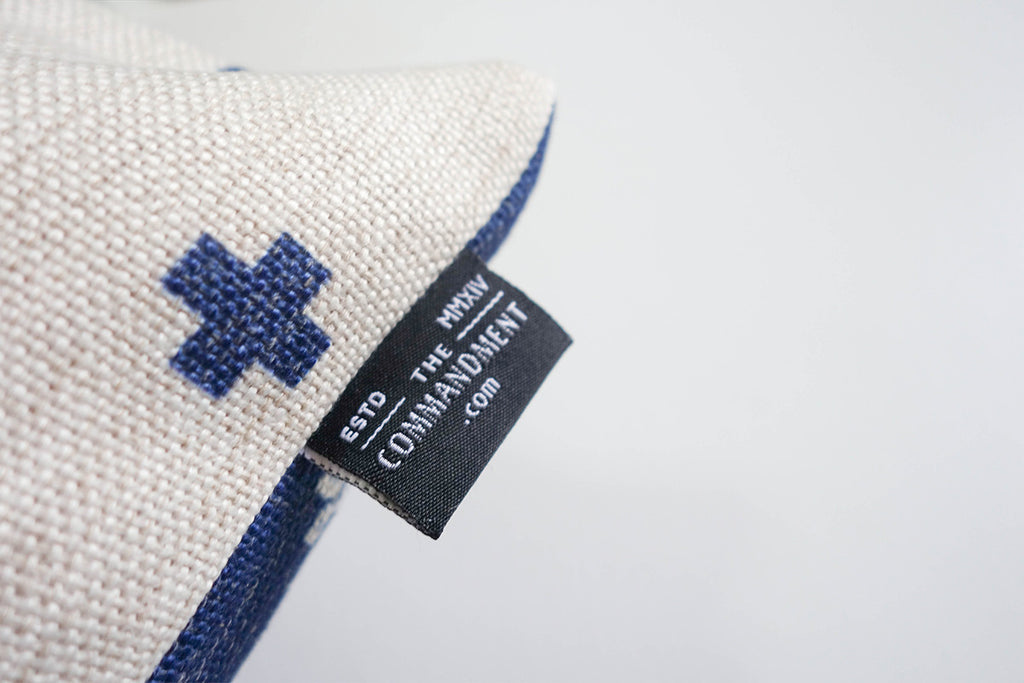 Close up of The Commandment Co back logo which features its website sewn on the pillow cover 