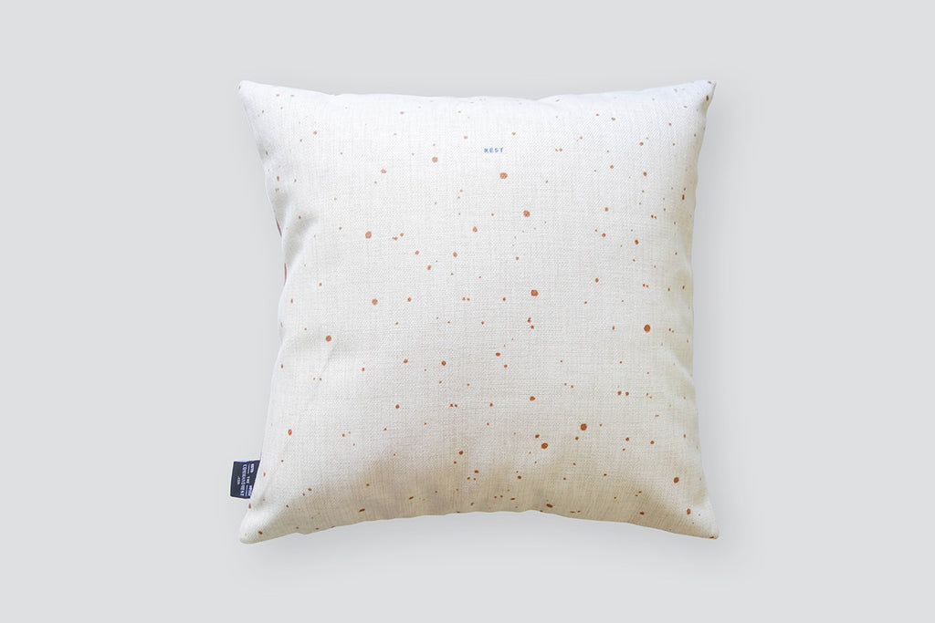 the back of the cushion cover features white background with sandy details.