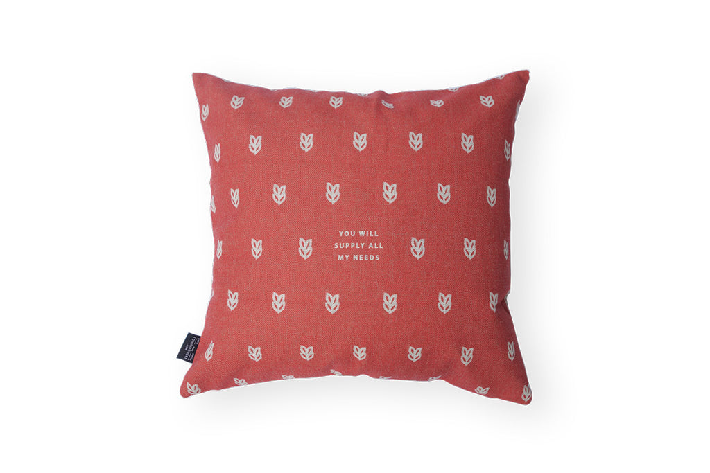 The back of the cushion features a red background and grey wheat and verse design