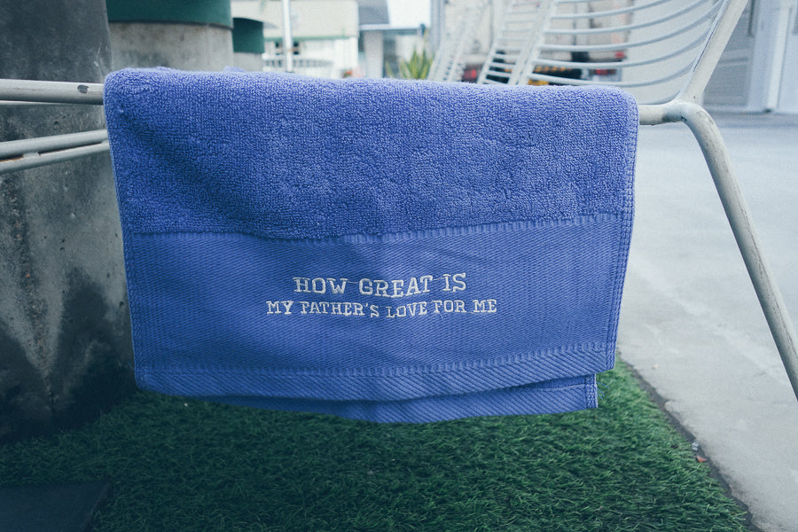 Blue sports towel hanging on handle of chair on top of grass patch