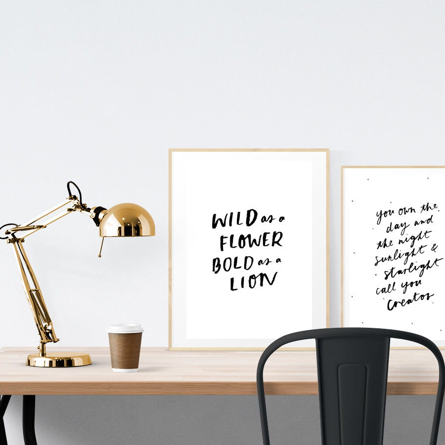A3 beautiful calligraphy poster placed standing next to a smaller A4 sized calligraphy poster on a wooden table. BnW Christian home interior design ideas.