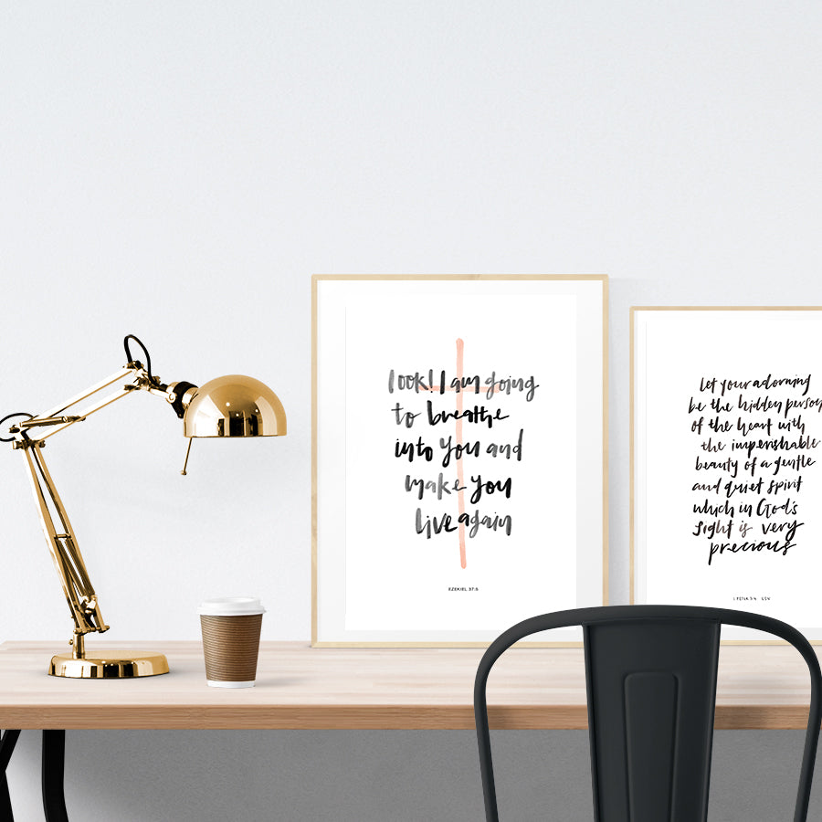 A3 beautiful calligraphy poster placed standing next to a smaller A4 sized calligraphy poster on a wooden table. Modern home interior design ideas. Minimalistic home decor ideas.