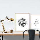 A3 beautiful calligraphy poster placed standing next to a smaller A4 sized calligraphy poster on a wooden table. Modern Christian home interior design ideas.