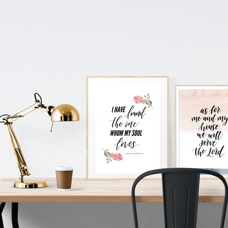 A3 beautiful calligraphy poster placed standing next to a smaller A4 sized calligraphy poster on a wooden table. Rustic Christian home interior design ideas.