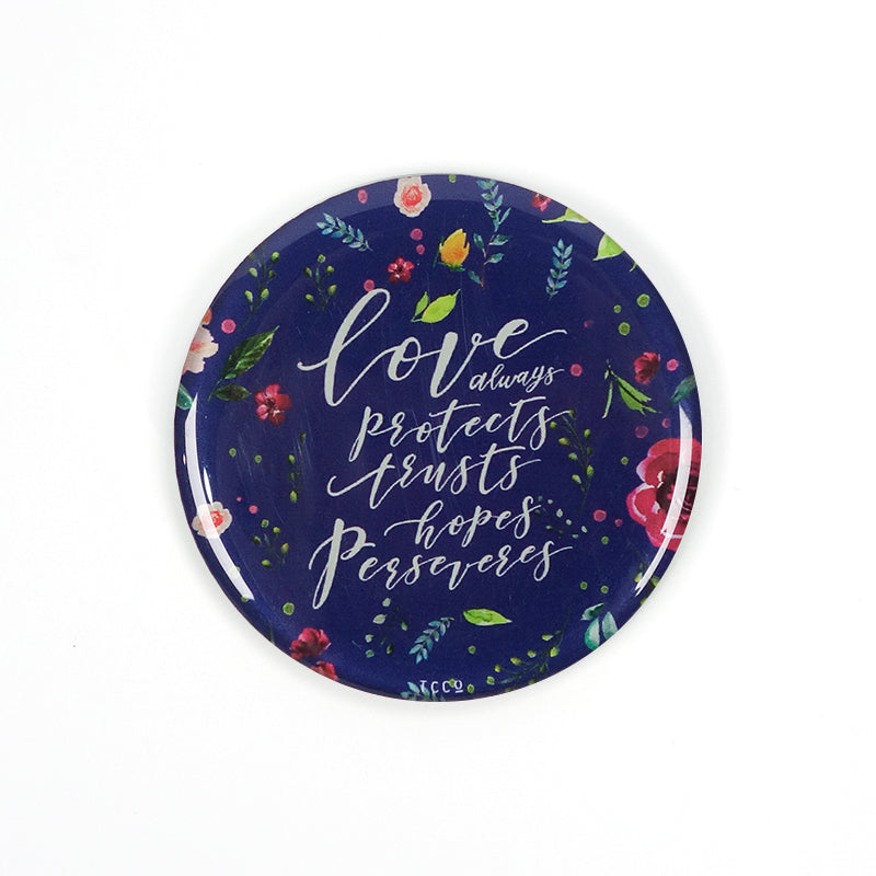 5.5 cm diameter circular Acrylic fridge magnet with bible verse “Love always protects, trusts, hopes perseveres” on foliage background.