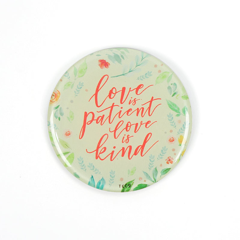 5.5 cm diameter circular Acrylic fridge magnet with bible verse “Love is patient love is kind” on foliage background.