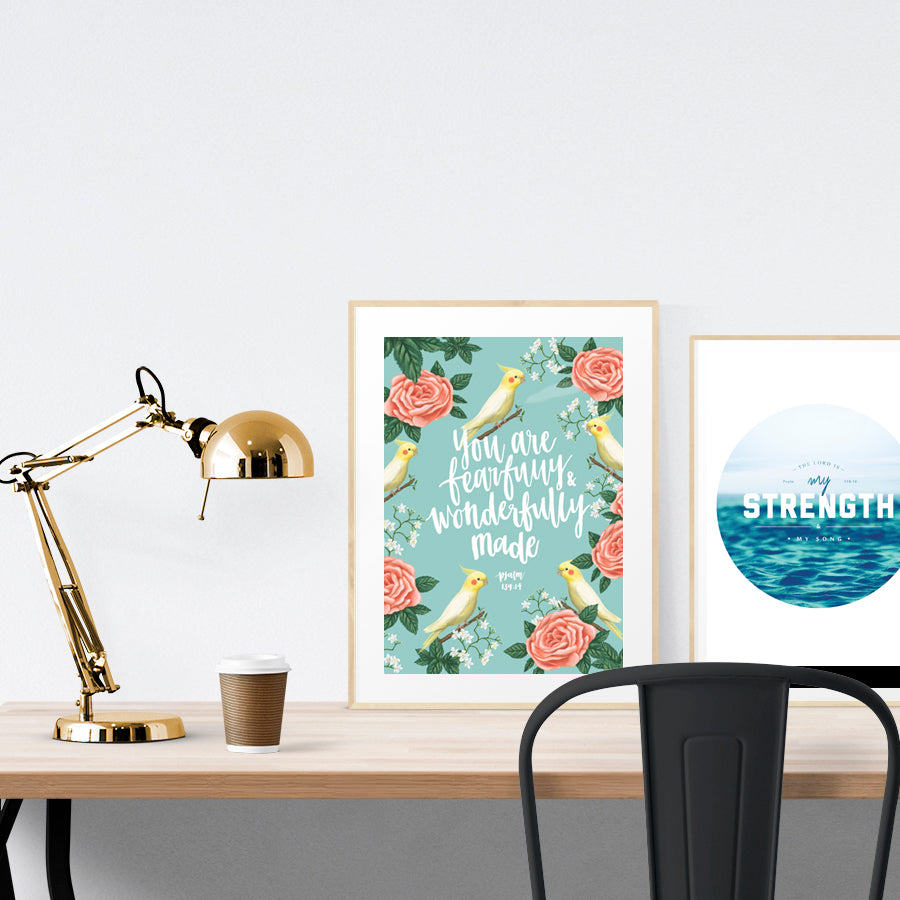 A3 calligraphy poster placed standing next to a smaller A4 sized calligraphy poster with on a wooden table. Inspiring home decor ideas.