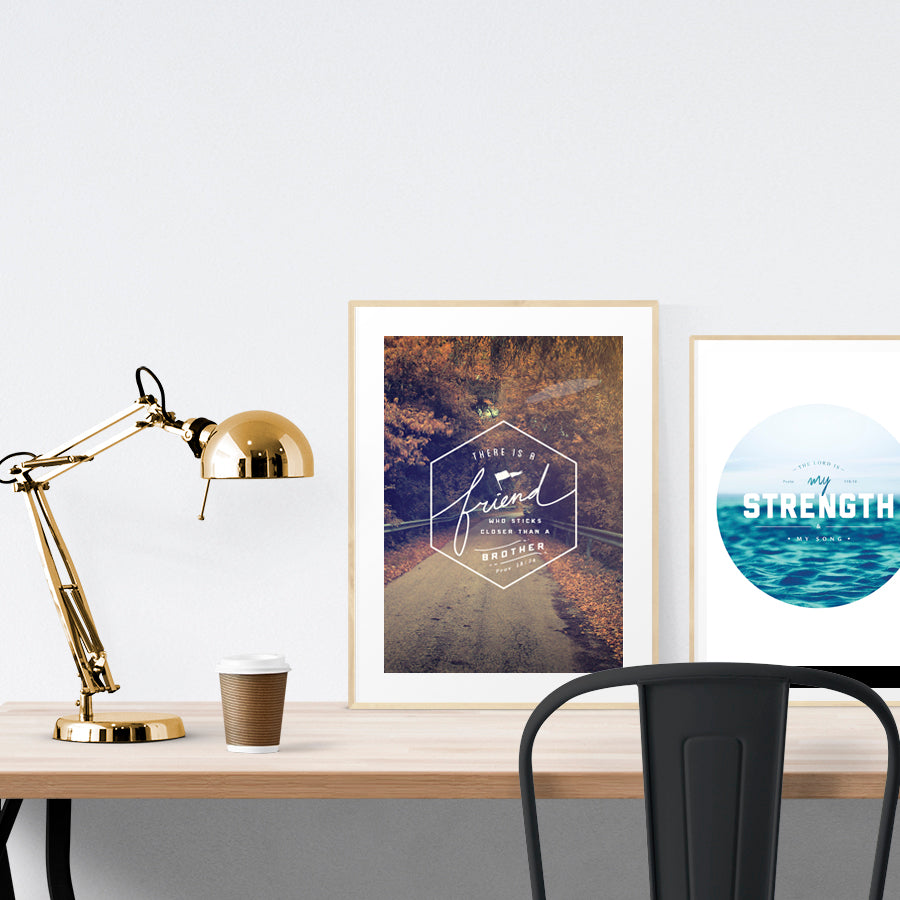 A3 beautiful calligraphy poster placed standing next to a smaller A4 sized calligraphy poster on a wooden table. Modern home interior design ideas.