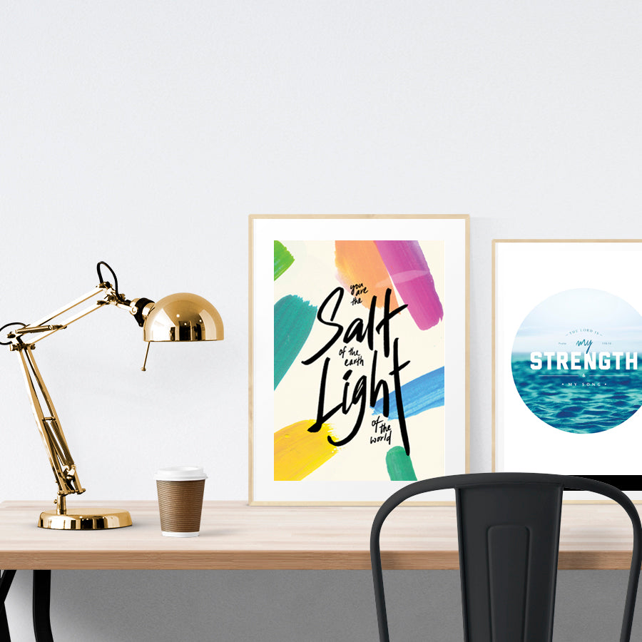A3 beautiful calligraphy poster placed standing next to a smaller A4 sized calligraphy poster on a wooden table. Modern home interior design ideas.