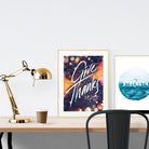A3 calligraphy poster placed standing next to a smaller A4 sized calligraphy poster with on a wooden table. Inspiring home decor ideas.